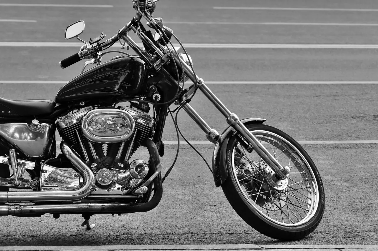 A detailed black and white photo of a chrome motorcycle parked on the road.