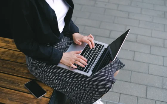 Woman sitting outdoors typing on a laptop, embodying freelance and digital nomad lifestyle.