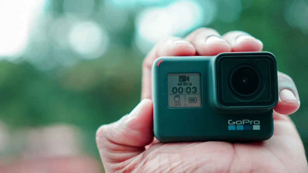 Detailed shot of a hand holding a compact action camera outdoors, ready for adventure.