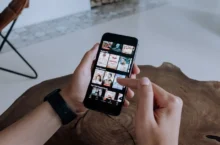 A person using a iphone to explore and select shows on a streaming platform indoors